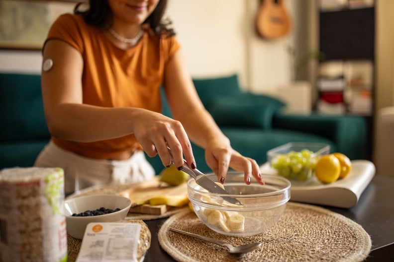 Young diabetic patient teenage woman preparing a healthy meal at home, she has a glucose monitor on her arm.