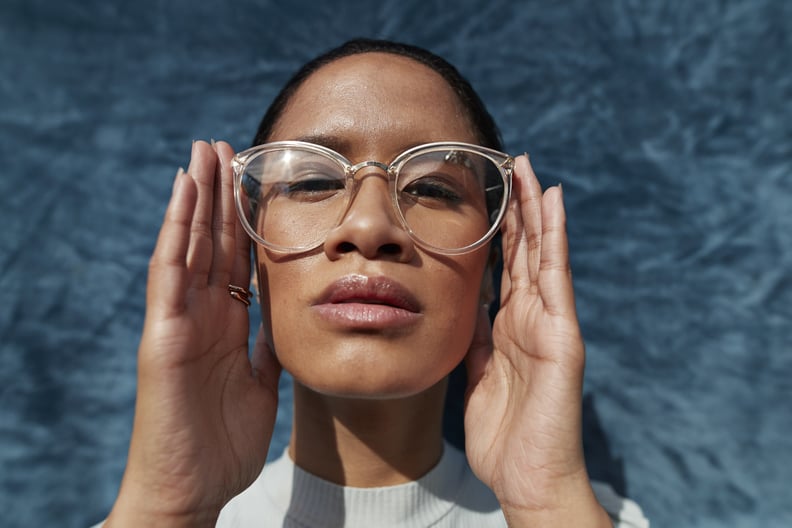 Woman wearing eyeglasses against blue wall.