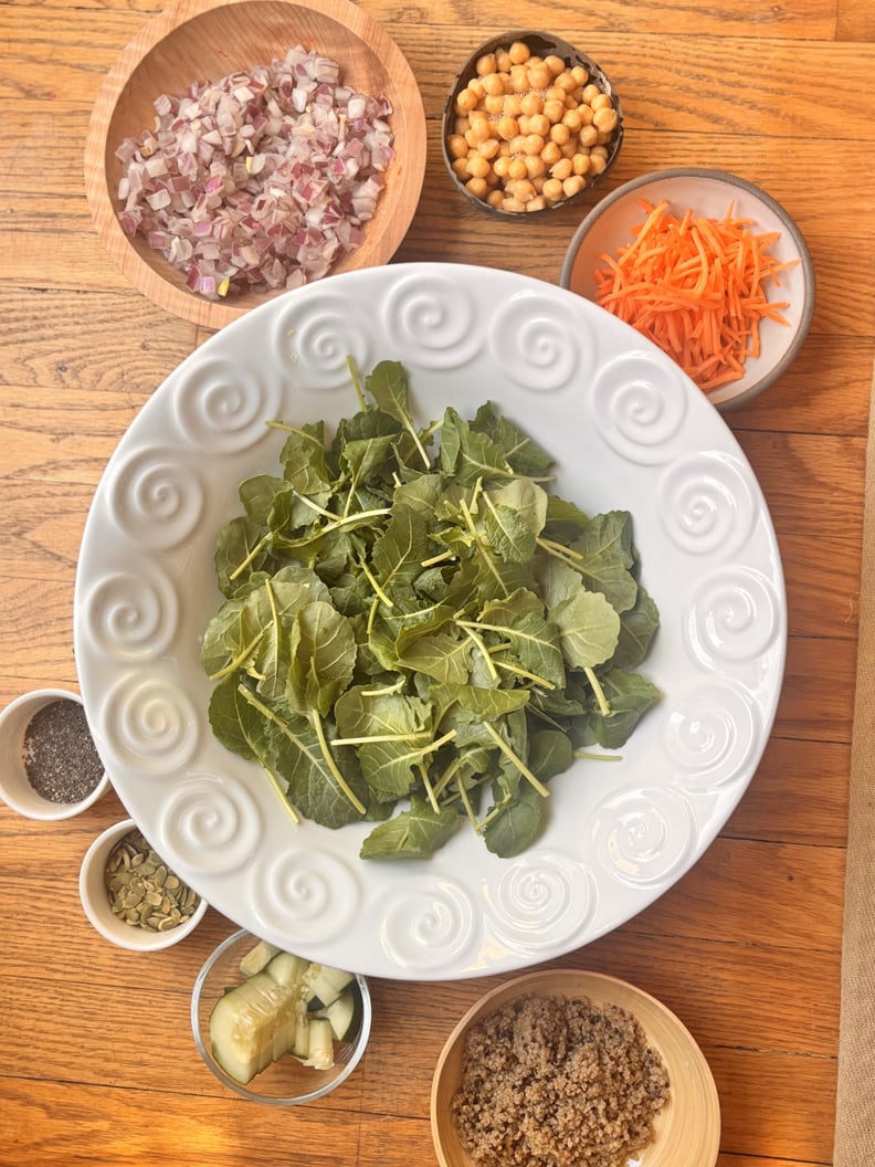 Salad in white bowl surrounded by ingredients including carrots, onions, chickpeas, and more.