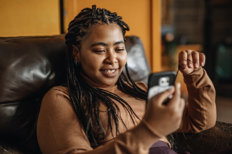 Woman With Braids Smiling at Her Phone